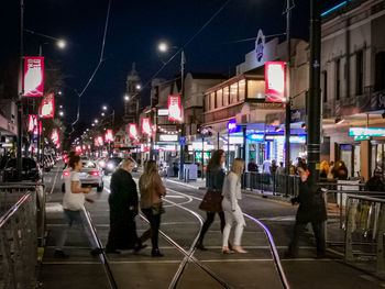 People walking on city street at night