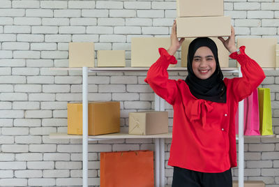 Portrait of a smiling young woman standing against brick wall