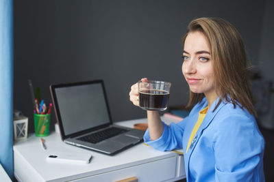 Smiling businesswoman drinking coffee sitting at office