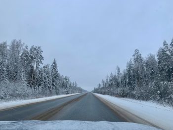 Road amidst snow covered trees against sky