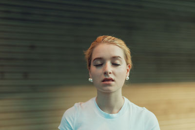 Young woman standing against wall