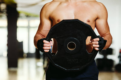 Midsection of shirtless man exercising in gym