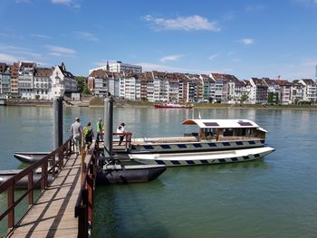 Boats in river by buildings in city against sky