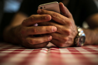 Midsection of man using phone while sitting at table