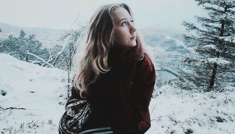 BEAUTIFUL YOUNG WOMAN LOOKING AT SNOW COVERED LAND