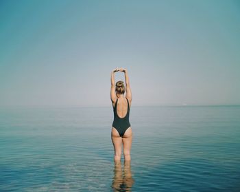 Rear view of woman in sea against clear sky