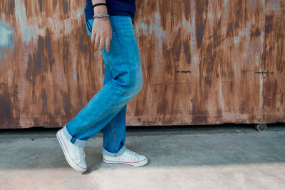 Low section of man standing against blue wall