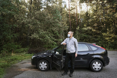 Portrait of man standing on road in forest