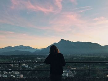 Rear view of woman standing on mountain against sky