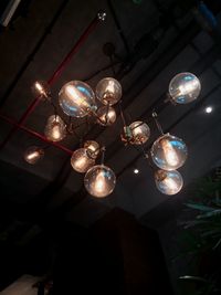 Low angle view of illuminated light bulbs hanging from ceiling