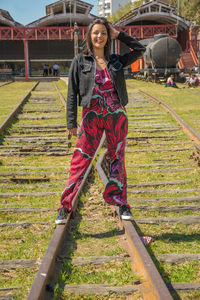 Portrait of smiling woman standing on railroad track