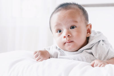 Close-up of cute baby boy lying on bed at home