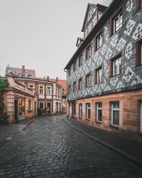 Cobblestone street amidst buildings against sky