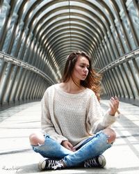 Young woman sitting on sidewalk in city