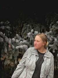 Portrait of woman standing in snow against trees during winter