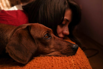 Close-up of sad woman and dog relaxing at home