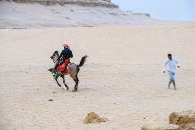 Man riding arabian horse on desert