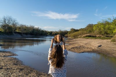 Woman standing in lake against sky