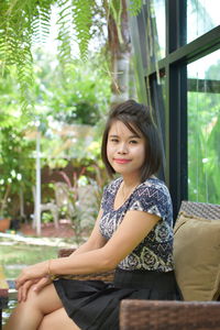 Portrait of young woman sitting on sofa outdoors