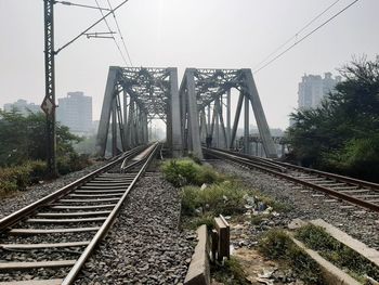 Railroad tracks by bridge against sky