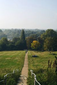 Rear view of man walking on field against sky