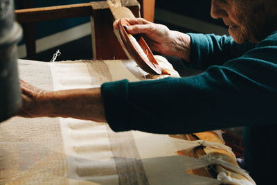 Cropped image of senior woman with loom in workshop