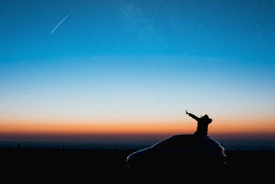 Young man sitting on car doing a dub in the blue hour of sunrise