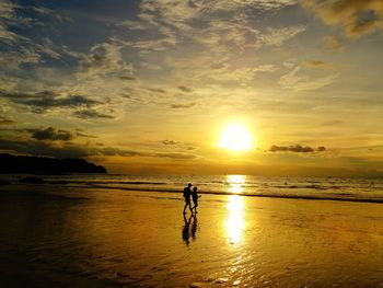 Silhouette man standing on beach against sky during sunset