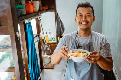 Portrait of young woman having food at home