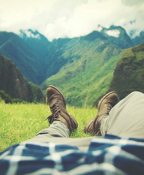 low section, mountain, person, shoe, personal perspective, lifestyles, leisure activity, landscape, men, mountain range, tranquility, grass, tranquil scene, footwear, nature, sky, standing