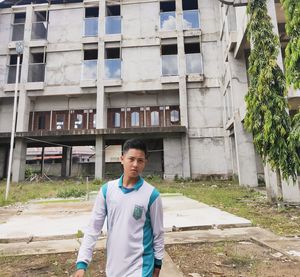 Young man standing against building