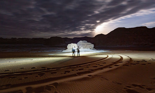 People on beach against sky during sunset