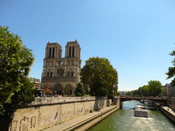 Canal amidst buildings against clear blue sky
