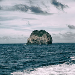 Rock formation in sea against sky