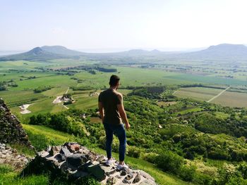 Rear view of man standing on landscape against sky