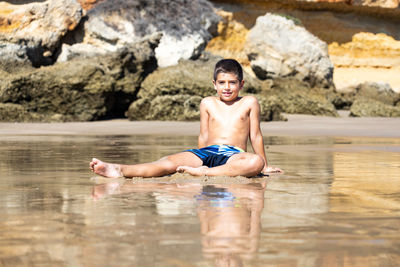 Little kid sitting on a rocky beach
