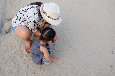 High angle view of mother and daughter playing with sand at playground