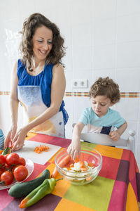 Woman preparing food while standing with son
