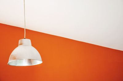 Lighting equipment hanging by orange and white wall