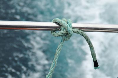 Close-up of rope tied on metal rail on boat