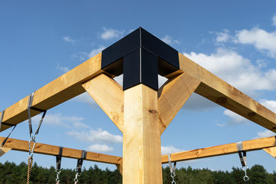 A modern cubic playground made of wooden logs and metal corners, visible steel corners.
