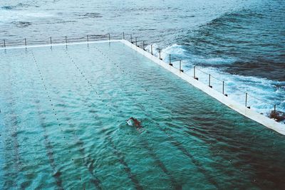 Man in swimming pool with calm sea in background