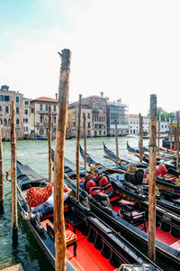 Boats moored in canal against sky in city