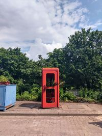 Telephone booth by trees against sky