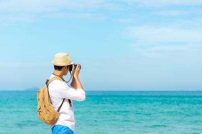 Woman photographing sea against sky