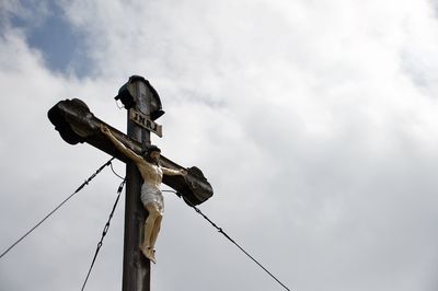 Low angle view of bird perching on cable against sky