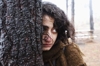 Portrait of woman against tree trunk