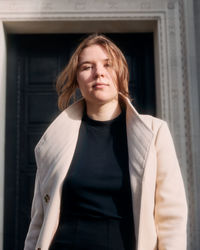 Portrait of young woman standing against wall