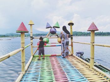 People on pier by sea against sky