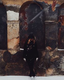 Full length of woman standing against weathered building during winter